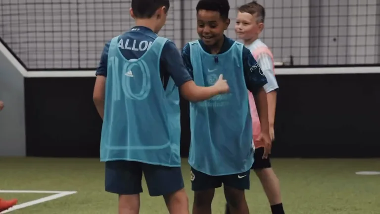 Two players in teal training bibs share a laugh during a session at Prestige Indoor Sports