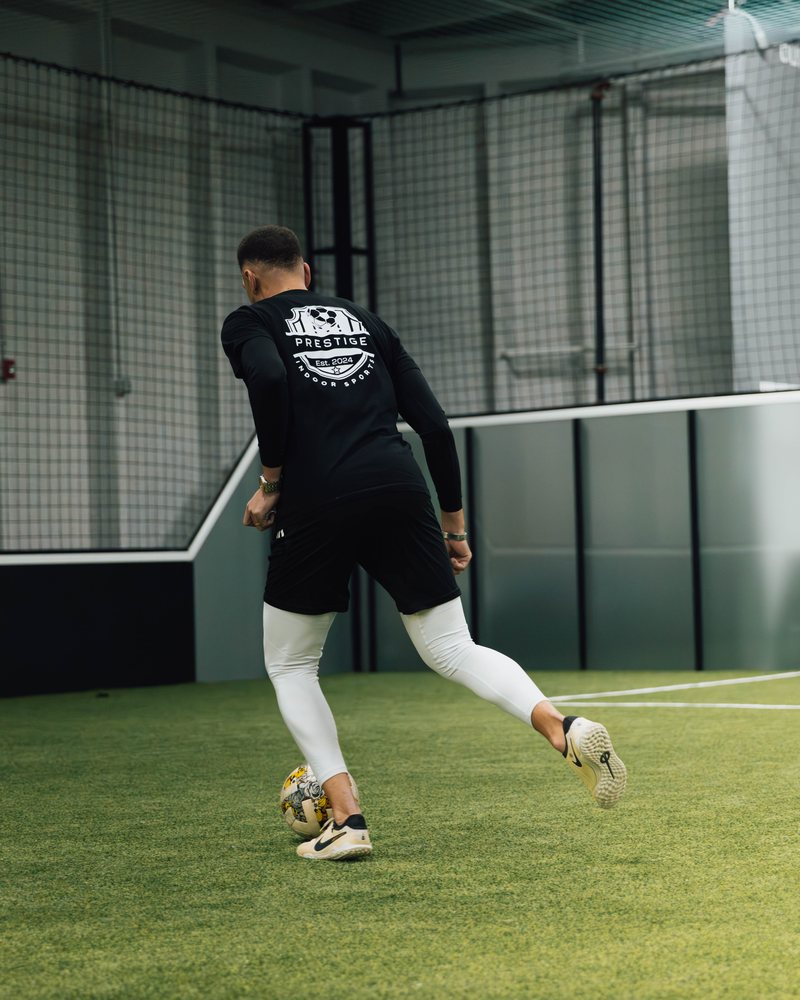 A Prestige coach in a Prestige shirt striking the ball on the indoor field