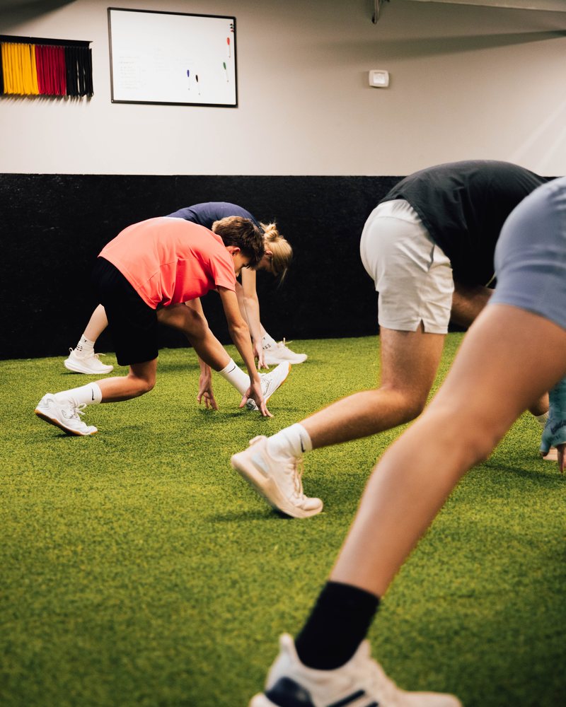 Players stretching into a sprint start during a training session at Prestige Indoor Sports